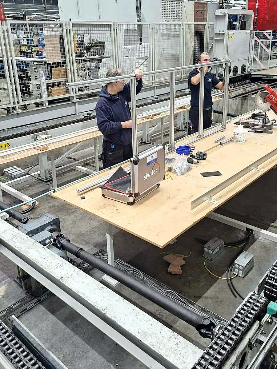 Dvojica montera sastavljaju aluminijsku ogradu uz transportnu liniju